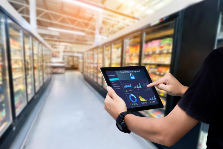 Smart retail management system. Worker hands holding tablet on blurred supermartket as background