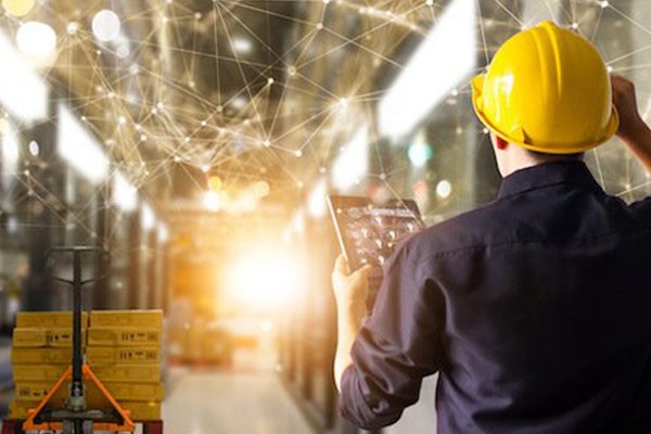 Warehouse worker with handheld screen overseeing premise